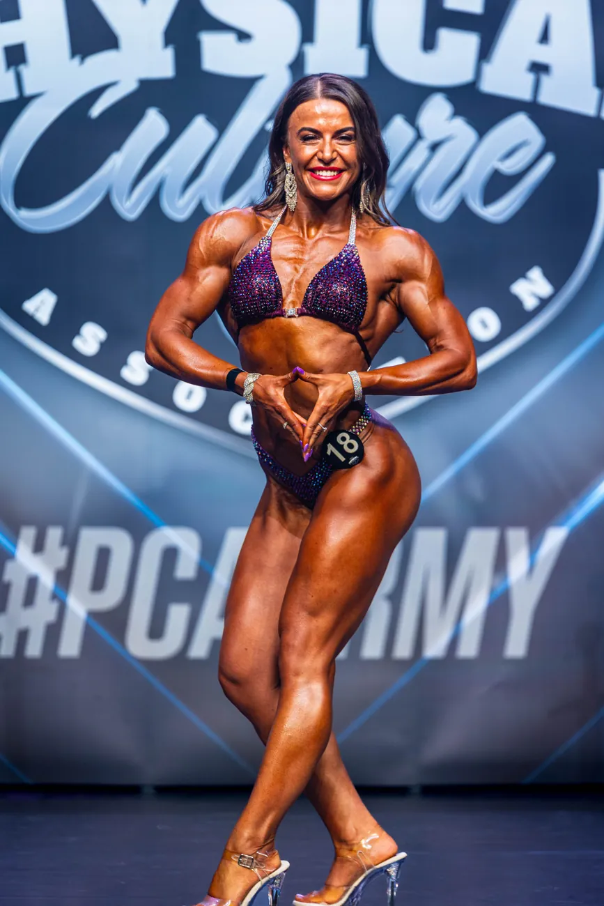 Athlete in a front pose on stage in a purple bikini
