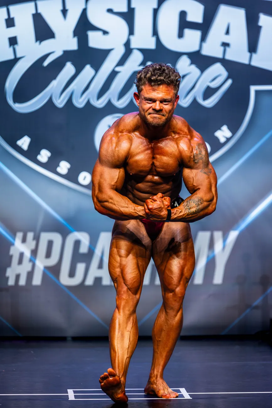 Bodybuilder in a most muscular pose on stage