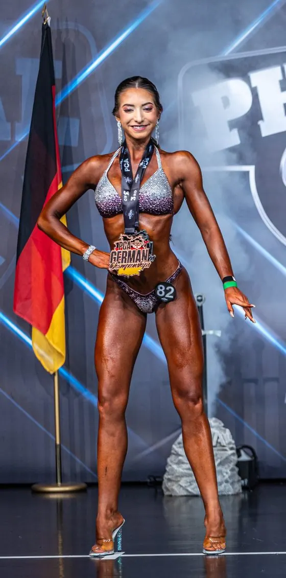 Medal winner posing on stage in a sparkling bikini